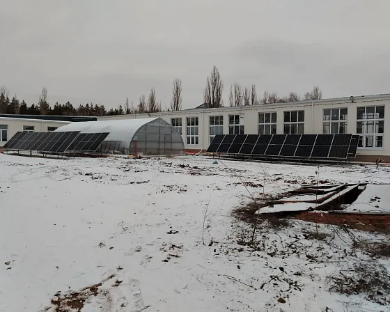 Теплица рядом с корпусом техникума, по обе стороны — две группы солнечных модулей